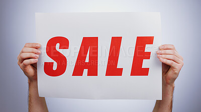 Sale, sign and hands with a poster, promotion and announcement of discount in studio with white background. Retail, shopping and person advertising with news, banner and deal for commercial savings