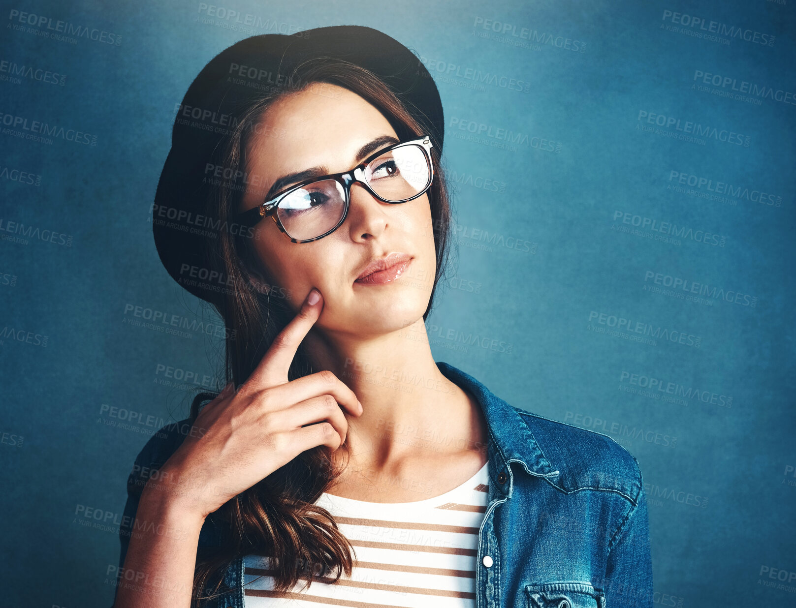 Buy stock photo Studio shot of an attractive young woman looking thoughtful against a blue background