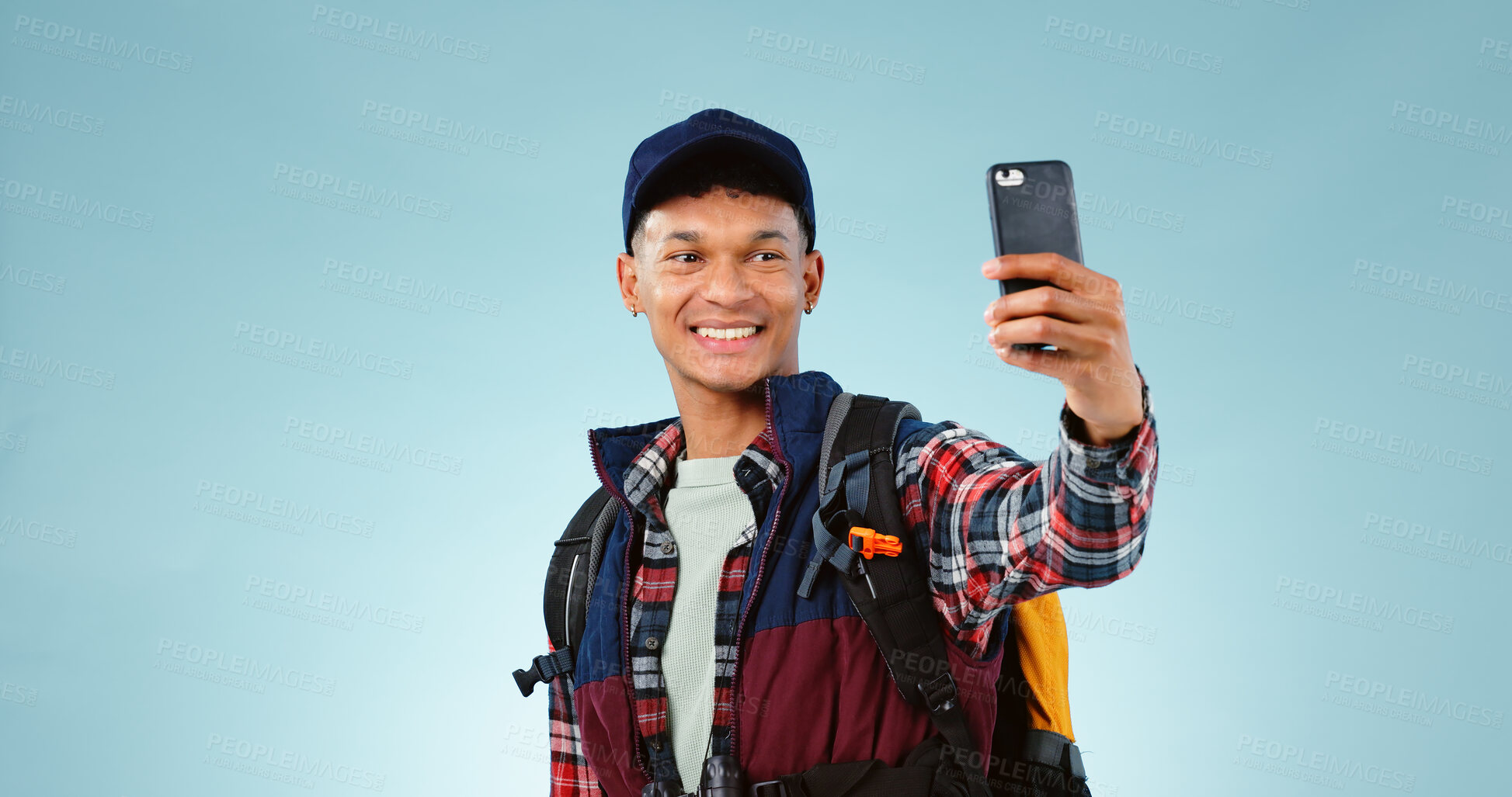 Buy stock photo Man, hiking selfie and smile in studio with backpack, gear and post on web blog by blue background. Influencer person, camping or trekking with photography for memory, profile picture or social media