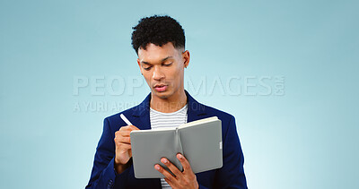 Buy stock photo Man in studio, writing in notebook for business ideas and research for creative startup schedule. Thinking, agenda and young professional businessman with notes, pen and to do list on blue background