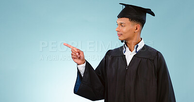 Buy stock photo Education, graduation and a student man pointing to space in studio on a blue background for marketing. School, university or college with a confident young graduate on mockup for advertising