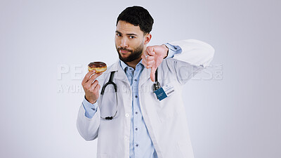 Buy stock photo Man, doctor and thumbs down for donut choice in studio and unhealthy snack in mockup. Mexican person, nutritionist and portrait or no, advice and opinion on diet, fail and food by gray background