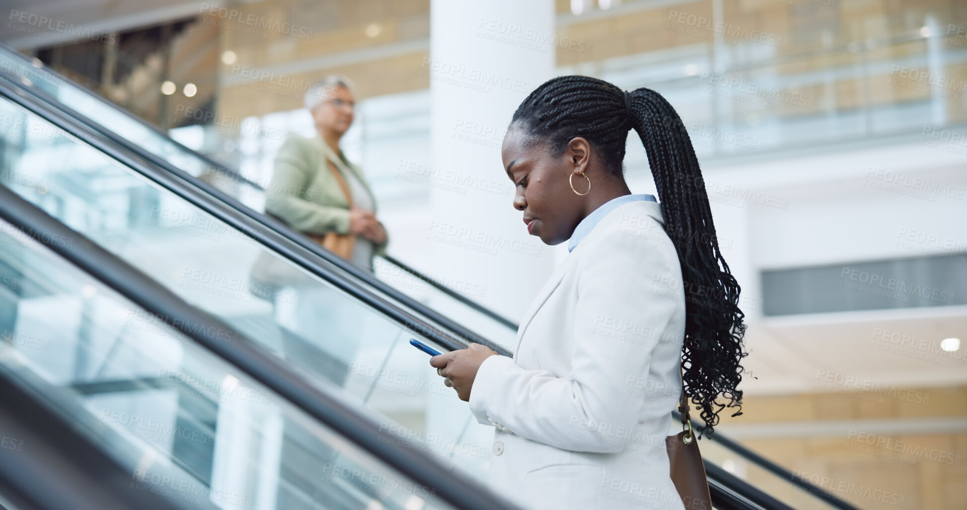 Buy stock photo Business, woman and phone on escalator for travel, meeting or communication in office building. Black person, entrepreneur and smartphone in modern workplace for commute, networking or text message