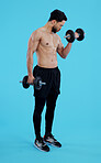 Fitness, dumbbells and man in studio for training, exercise or bodybuilding on blue background. Health, wellness and topless guy bodybuilder with bicep workout, muscle or flex, progress or resilience