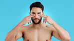 Skincare, portrait and man with eye patches for anti ageing treatment isolated on blue background. Care, skin and face of model with collagen mask on eyes, dermatology and luxury spa facial in studio