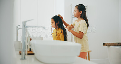 Buy stock photo Family, bathroom and a girl brushing the hair of her sister in their home for morning routine or care. Kids, beauty or haircare with a young child and helping sibling in their apartment for love