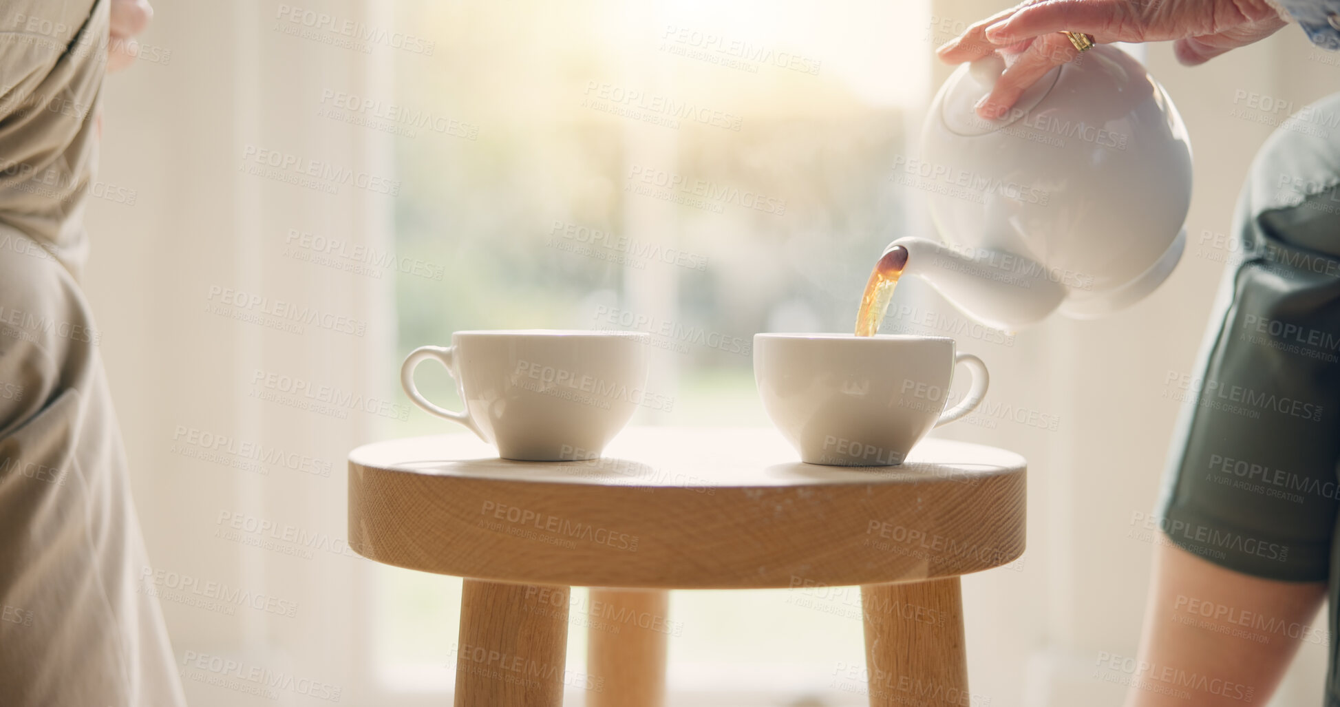 Buy stock photo Pot, pour and hands with tea cup in morning, home and closeup on drink, steam and table. Hot, beverage and person with hospitality, service and drinking in the afternoon with friends in living room