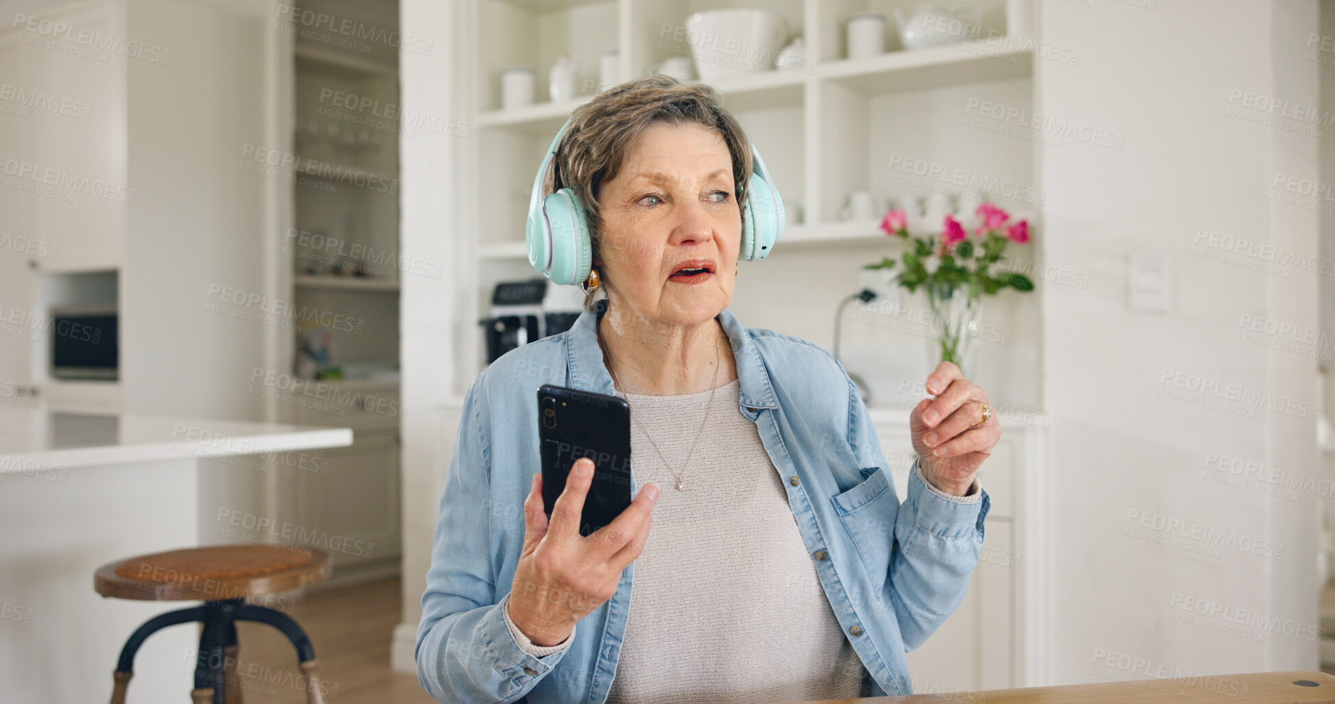 Buy stock photo Music, headphones and senior woman with phone in a kitchen for streaming, album or track at home. Smartphone, app and elderly lady person with earphones for online audio, radio or podcast in a house