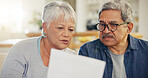 Senior couple, bills and reading paperwork in home for budget, planning investment and financial assets. Man, woman and discussion with documents for banking, retirement savings and insurance policy