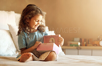 Buy stock photo Shot of an adorable little girl at home sitting on her bed and playing with a music box