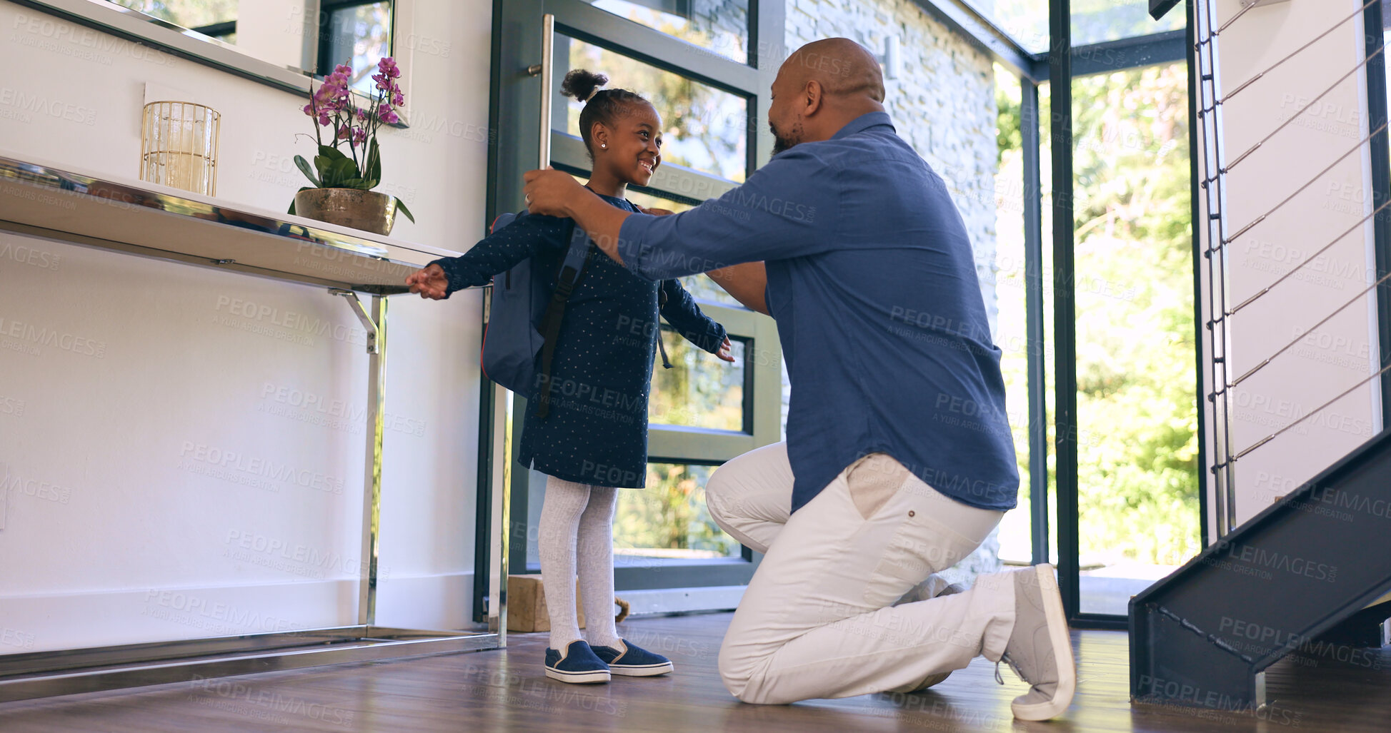 Buy stock photo Back to school, getting ready and a girl student with her dad in their apartment together to say goodbye. Black family, kids and a man parent helping his daughter with her backpack while leaving home