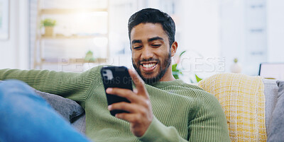 Buy stock photo Man, living room couch and happy with phone, smile and click for contact, meme and notification in home. Person, smartphone and texting for scroll, reading and app for social network, video and relax