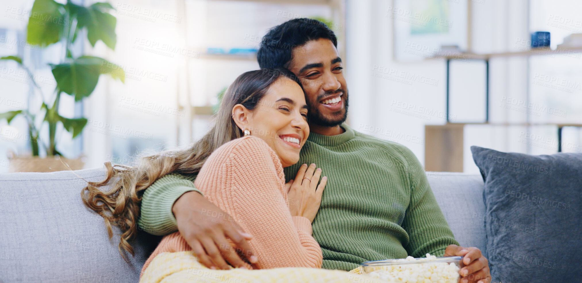 Buy stock photo Love, hug and couple on watching tv on a sofa with popcorn for movie, film or streaming show at home. Relax, television and people embrace in a living room with cinema snack for comedy or series