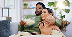Jump scare, hug and couple watching tv on a sofa with popcorn for movie, film or streaming show at home. Wow, television and people embrace in a living room with cinema snack for horror or series