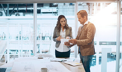Buy stock photo Cropped shot of two architects looking at a tablet while standing in their office