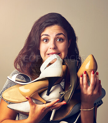 Buy stock photo Studio shot of a joyful young woman holding a lot of shoes against a brown background