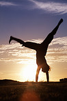 Sunrise, cartwheel and field with running with a happy person and travel outdoor with freedom. Vacation, holiday and fitness in the morning by the beach and grass with shadow and silhouette by sun 