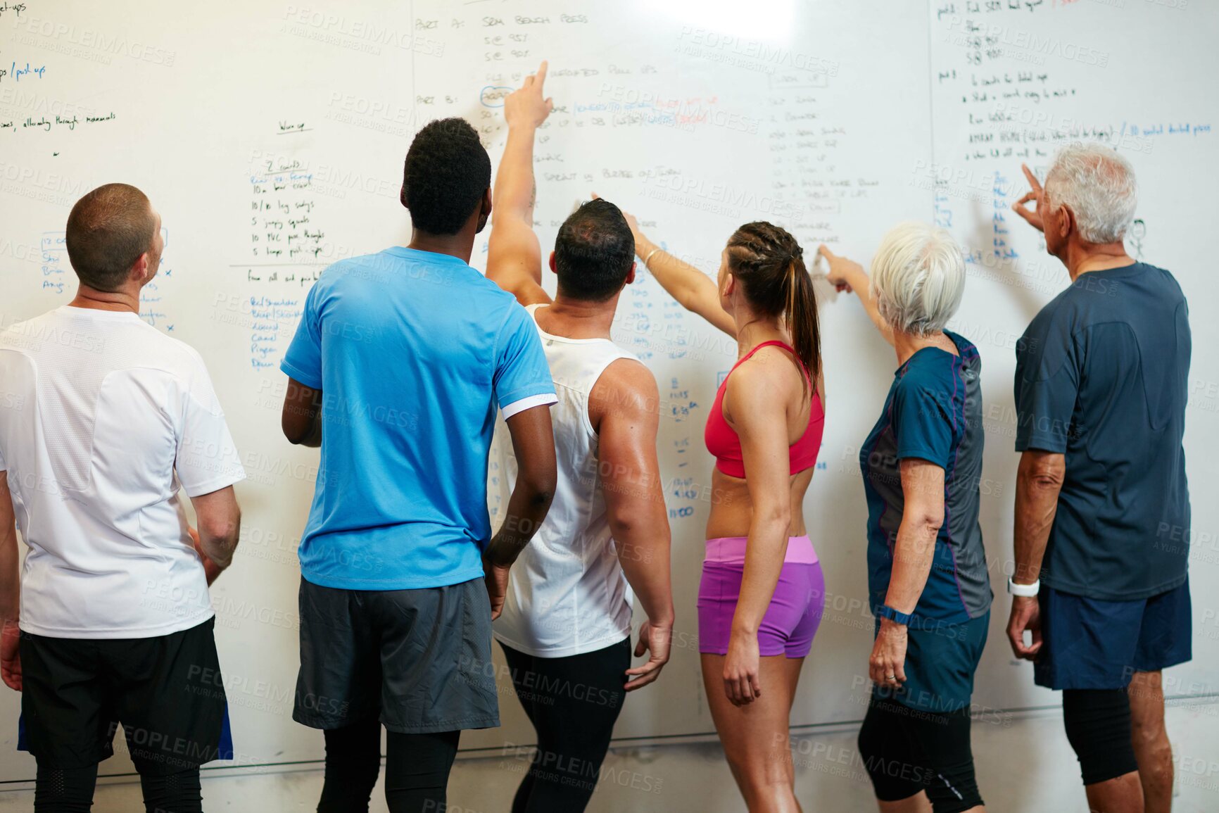 Buy stock photo Rearview shot of a group of people looking at a whiteboard while standing in the gym