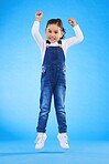 Jump, smile and portrait of a child in a studio with energy, achievement or good news with excitement. Happy, youth and full length of a girl kid model moving for winning by isolated blue background.