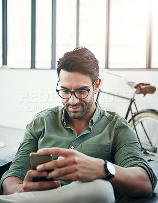Buy stock photo Shot of a design professional using his phone while sitting in an office