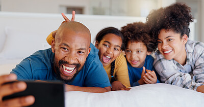 Buy stock photo Selfie, smile and children with parents in bed of modern home for bonding together with teddy bear. Happy, fun and young interracial man and woman laying for rest with kids in bedroom of family house