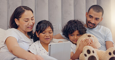 Buy stock photo Tablet, smile and children with parents in bed watching a video on social media together at home. Happy, bonding and young mother and father relaxing with kids in bedroom with digital technology.