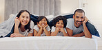 Portrait, smile and children with parents in bed relaxing and bonding together at family home. Happy, fun and young mother and father laying and resting with kids in bedroom of modern house.