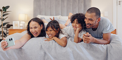 Buy stock photo Selfie, smile and children with parents in bed relaxing and bonding together at family home. Happy, fun and young mother and father laying and taking a picture with kids in bedroom of modern house.