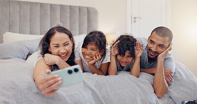 Buy stock photo Happy, selfie and children with parents in bed relaxing and bonding together at family home. Smile, fun and young mother and father laying and taking a picture with kids in bedroom of modern house.