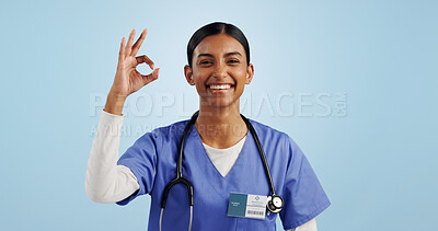 Buy stock photo Happy woman, okay or portrait of doctor with smile, pride or confidence isolated on blue background. Wellness, perfect or healthcare worker with approval sign, success or yes hand gesture in studio