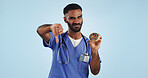 Man, portrait and doctor with thumbs down, donut and bad review for diet against a blue studio background. Male person or medical nurse showing rejection, no emoji or sign with chocolate dessert