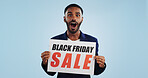 Surprised man, portrait and sale sign for advertising, deal or discount against a blue studio background. Shocked male person with billboard, poster or wow in marketing, promo or Black Friday special