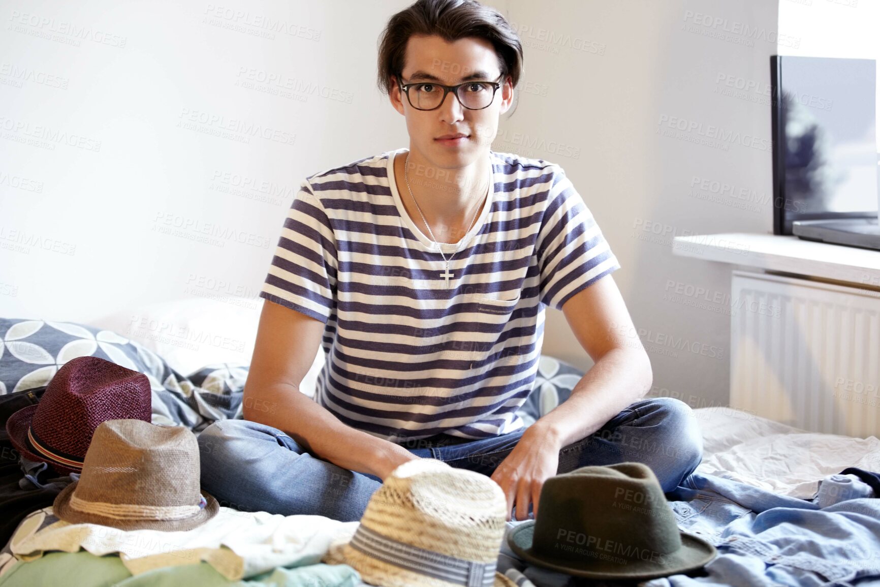 Buy stock photo Fashion, hats and portrait of man in bedroom with fedora collection in home and apartment with nerd. Geek, style and person on bed with choice of vintage hat with trendy glasses and planning outfit