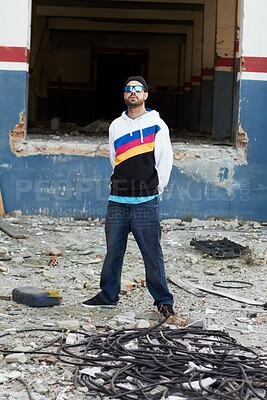 Buy stock photo A trendy male standing in front of a graffiti wall in a junkyard