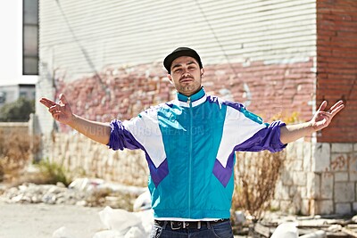 Buy stock photo Graffiti artist, city and portrait of man in street stand by art, illustration and creative wall design. Fashion, gangster and person with hand sign in trendy, urban streetwear and casual clothes