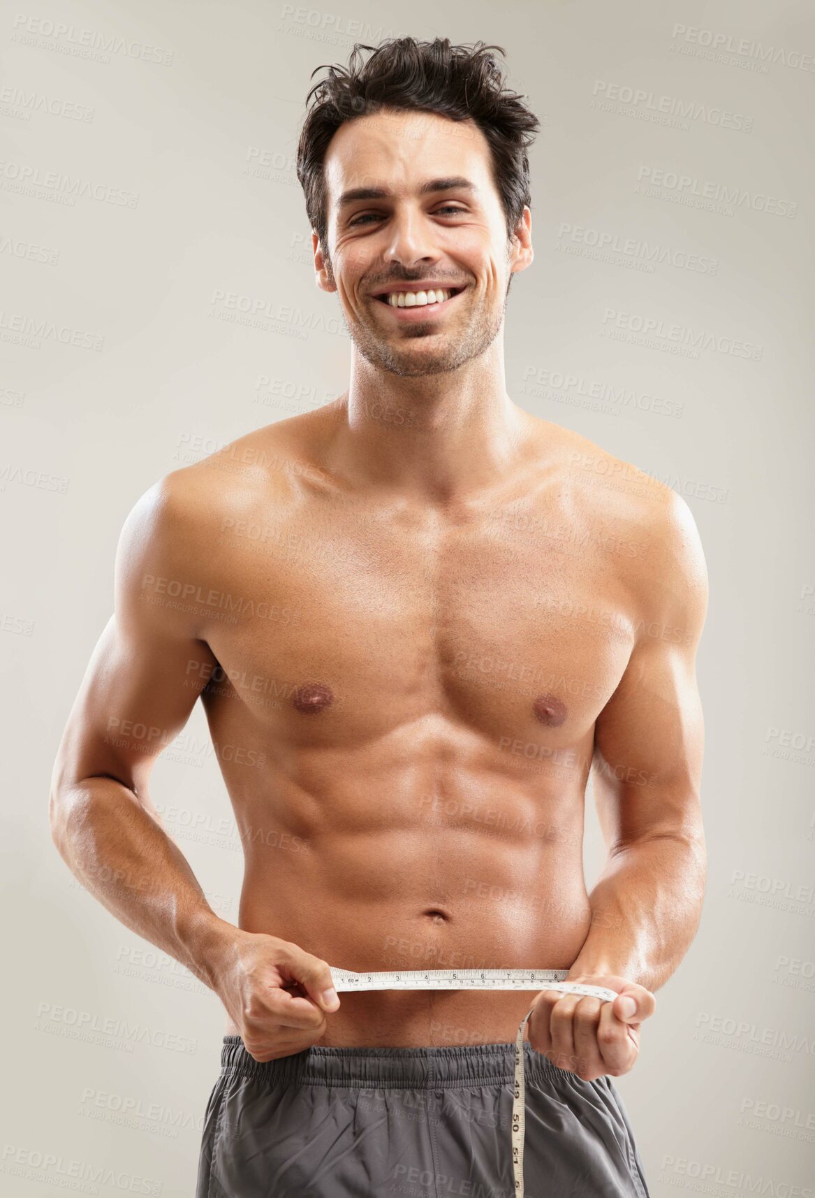 Buy stock photo Portrait of a hunky young man measuring his waist
