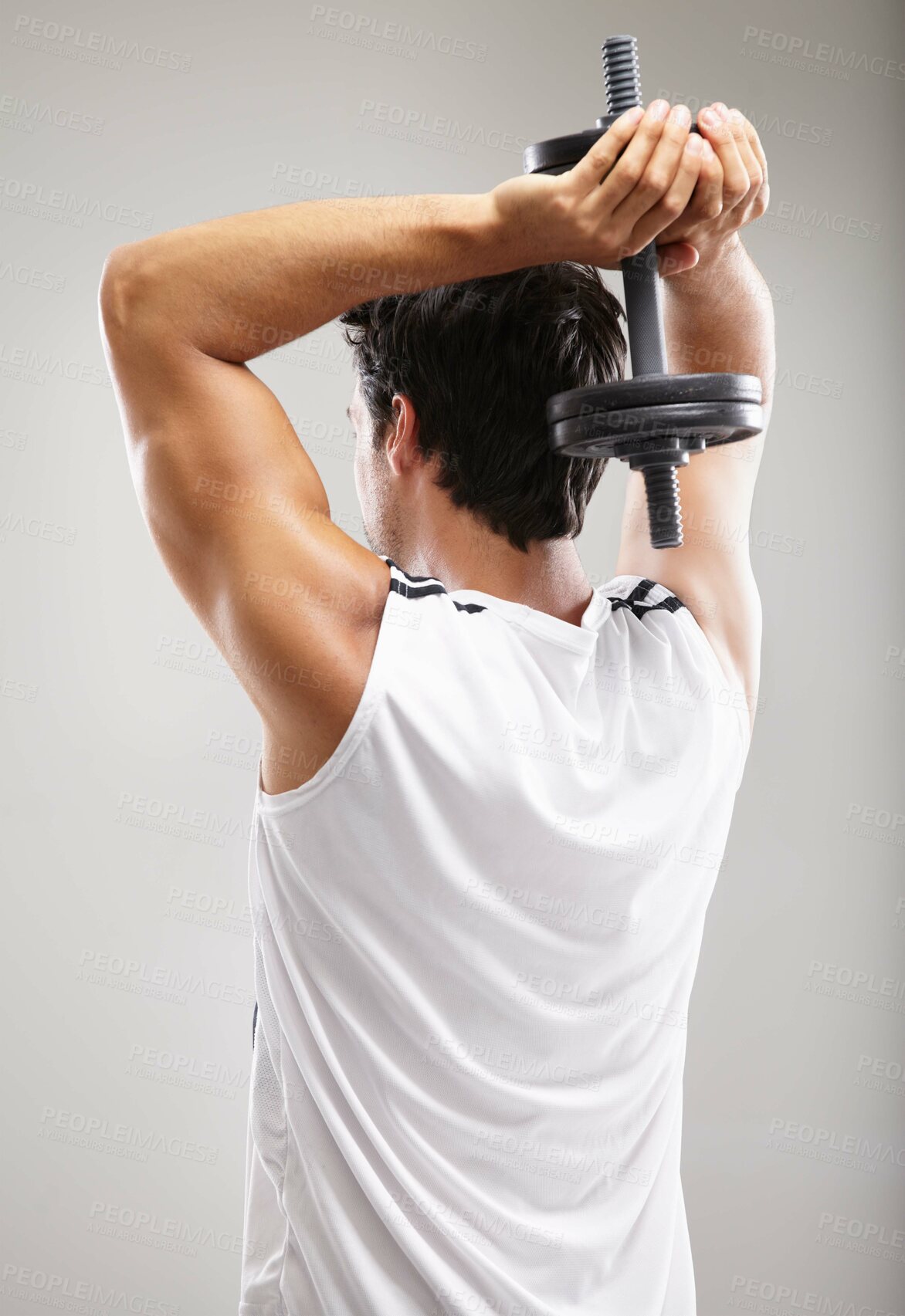 Buy stock photo Rearview of a young man using dumbbells to strengthen his triceps