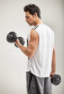 Buy stock photo A handsome young man training with dumbbells