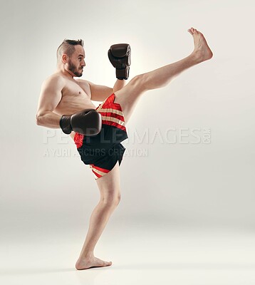 Buy stock photo An MMA fighter kicking while isolated on white
