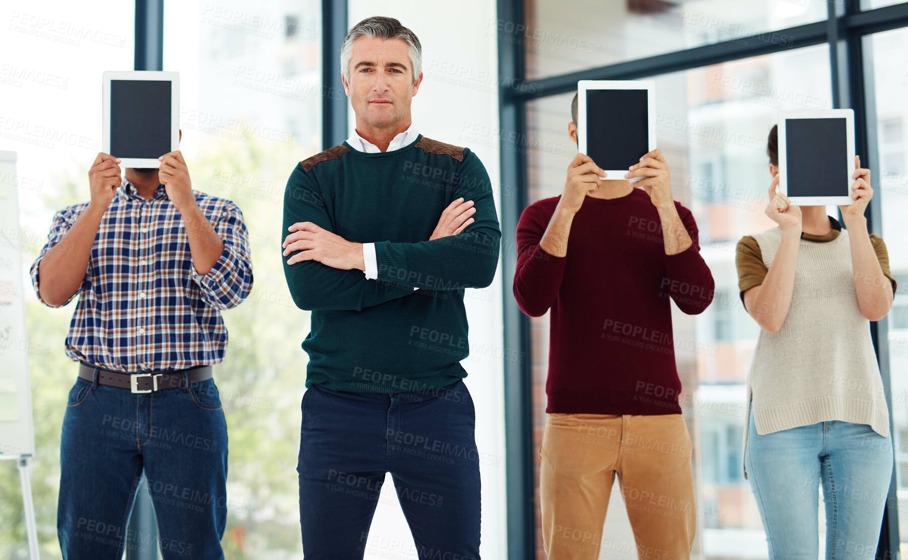 Buy stock photo Cropped portrait of a mature businessman standing with his colleagues who are covering their faces with tablets