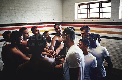 Buy stock photo Cropped shot of a group of handsome young rugby players standing together in a huddle in a locker room