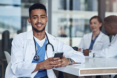 Buy stock photo Shot of a young male doctor using his smartphone while taking a break