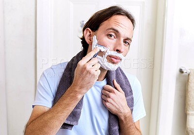 Buy stock photo Shot of a young man shaving his face in the morning