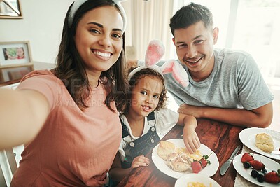 Buy stock photo Shot of a young couple taking a selfie while having breakfast with their daughter at home