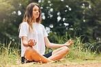 Young caucasian woman meditating while exercising outdoors. One female only practising yoga to stay calm and relaxed in body, mind and soul. Focused on breathing during workout at the park or forest