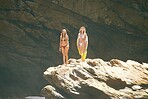 Summer, bikini and holiday, women on a cliff in the sun, ready to jump into the water. Travel, beauty and adventure, young girls relax on vacation in the sun with rock face or cave in the background.