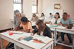 School, students and classroom with teacher help, answer and explain during lesson with young group. Education, study and elderly woman teaching, checking and showing and helping pupil textbook exam 