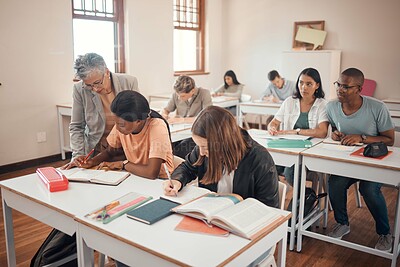 Buy stock photo School, students and classroom with teacher help, answer and explain during lesson with young group. Education, study and elderly woman teaching, checking and showing and helping pupil textbook exam 