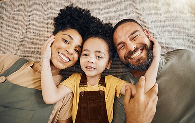 Buy stock photo Portrait, family and a boy with his parents on the floor of the living room in their home together from above. Face, smile or love with an interracial mother, father and son lying down closeup