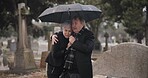 Support, death or old couple in cemetery for funeral, service or burial for repsect in Christian religion. Umbrella, depressed or sad senior people hug for comfort in graveyard crying in mourning